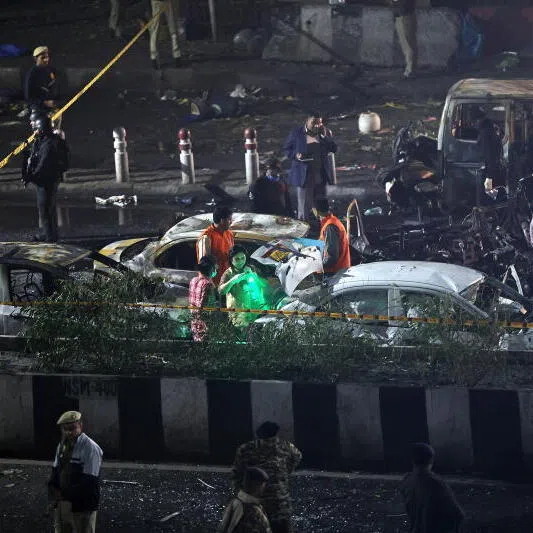 Indian police personnel inspect the scene of a blast near the red fort in New Delhi, India.