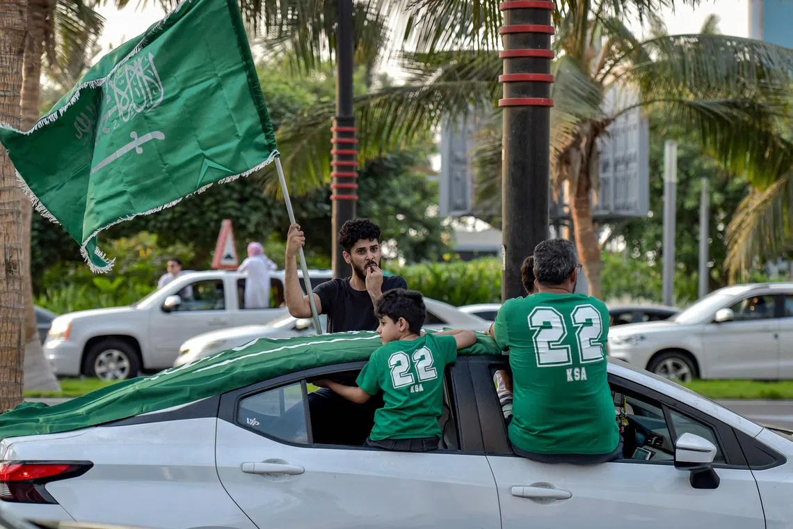 A fan waving the Saudi Arabia flag from the window of a car in Riyadh while celebrating the win over Argentina on Nov 22, 2022.