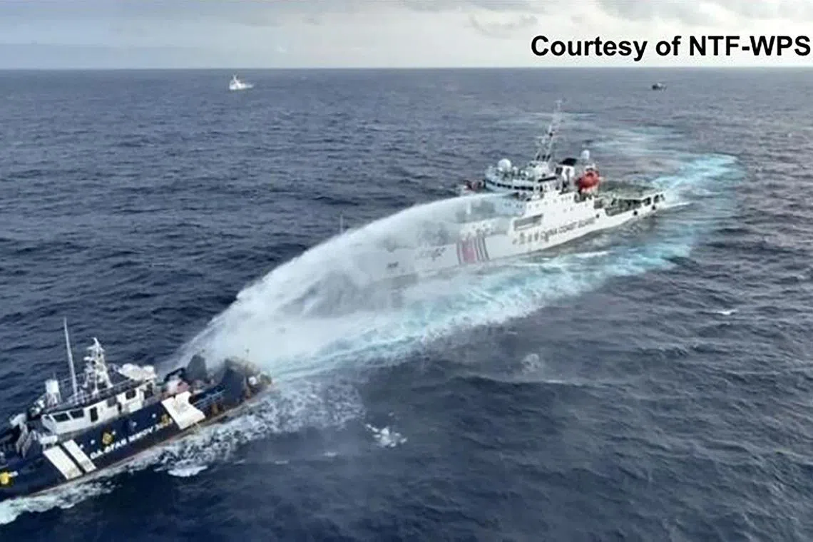 This handout taken and released on Dec 4 by the National Task Force for the West Philippine Sea (NTF-WPS) shows a China Coast Guard ship (right) deploying water cannon at the Phillipine Bureau of Fisheries and Aquatic Resources (BFAR) vessel BRP Datu Pagbuaya (L) near Scarborough Shoal in disputed waters of the South China Sea.  The Philippines and China have for years clashed over maritime rights in the South China Sea as well as possession of reefs and islets.