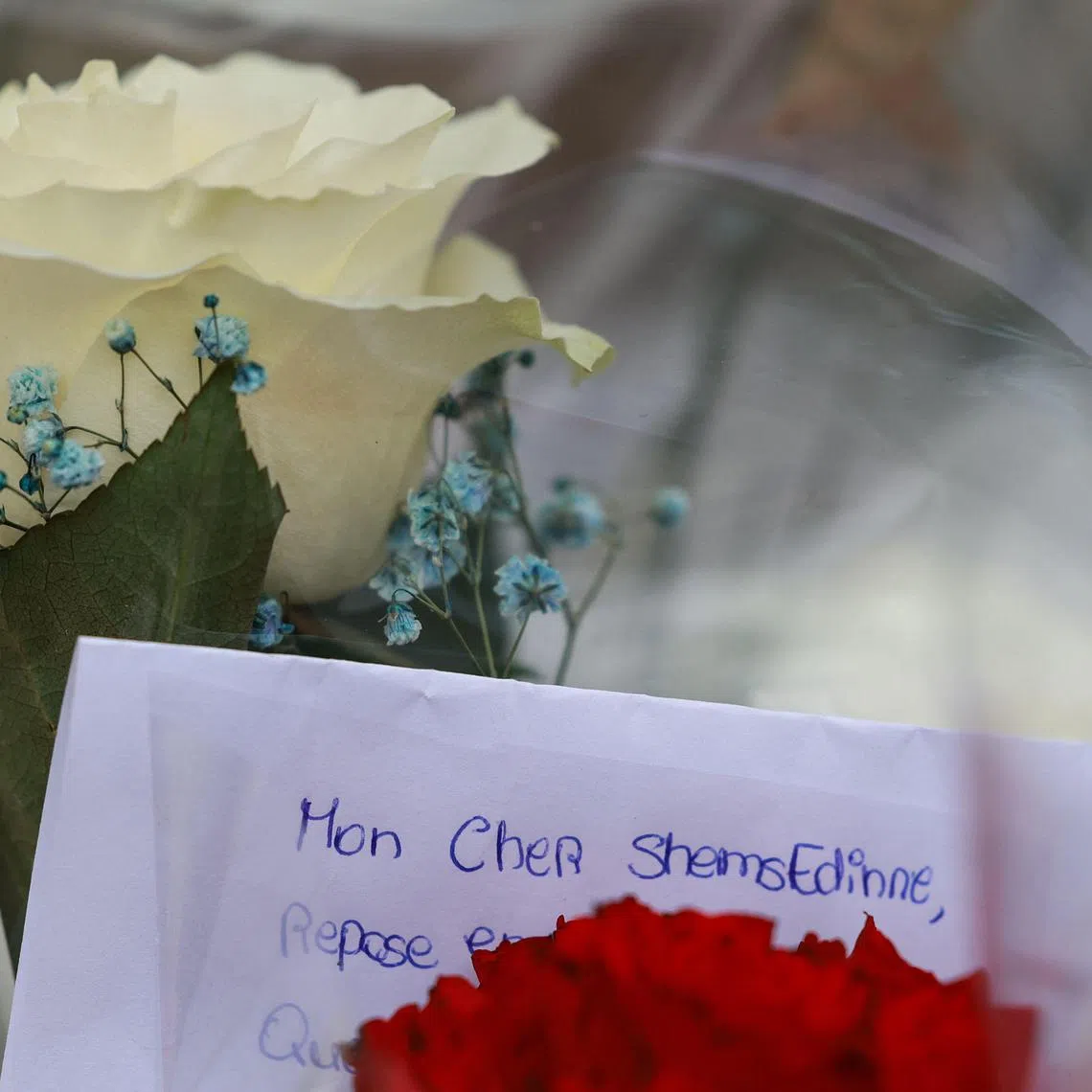 This photograph taken on April 7, 2024, shows flowers and a letter reading "My dear Shemsedinne" displayed as a tribute before the entrance of middle school Les Sablons in Viry-Chatillon, following the fatal beating of teeanage boy Shemseddine.