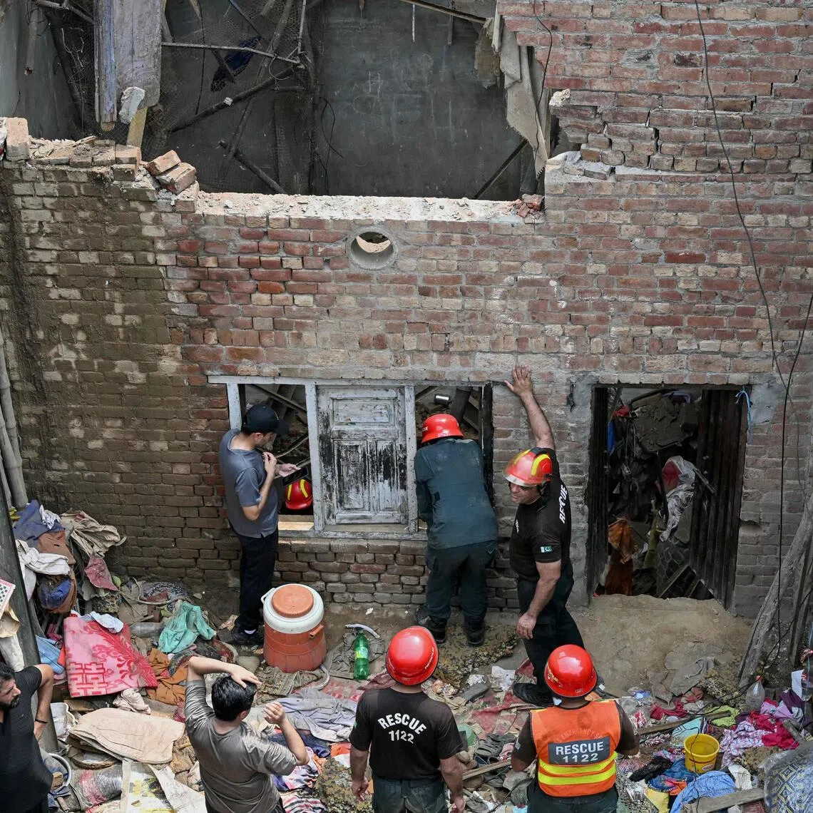 Rescue personnel conduct a search operation amid rubble after the roof of a house collapsed in Lahore on July 30.