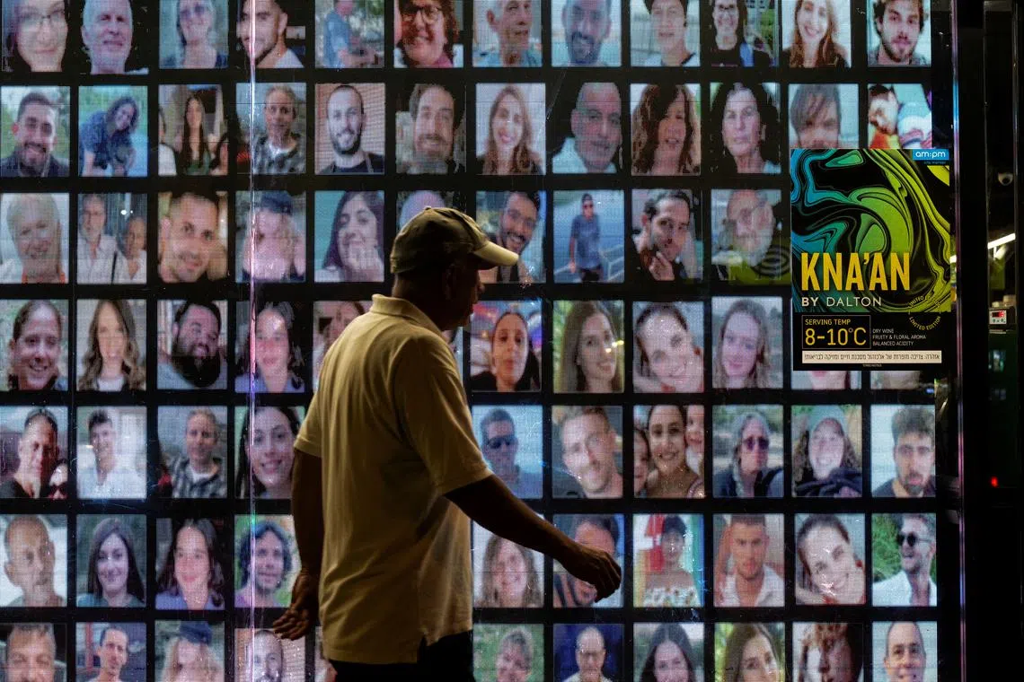 A person walks past pictures of hostages kidnapped during the deadly October 7 attack by the Palestinian Islamist group Hamas from Gaza, projected on a screen, in Tel Aviv, Israel, May 31, 2024. REUTERS/Marko Djurica