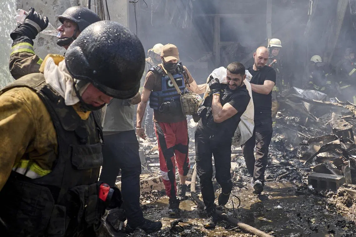 Rescuers carry the body of a victim of Russian  shelling from a printing house in Kharkiv, Ukraine.