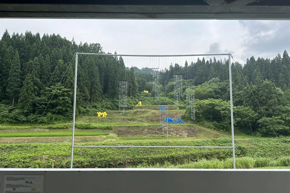 The Rice Fields by Ilya and Emilia Kabakov frames colourful minimalist sculptures of farmers on a terraced hillside of wokring padi fields. 