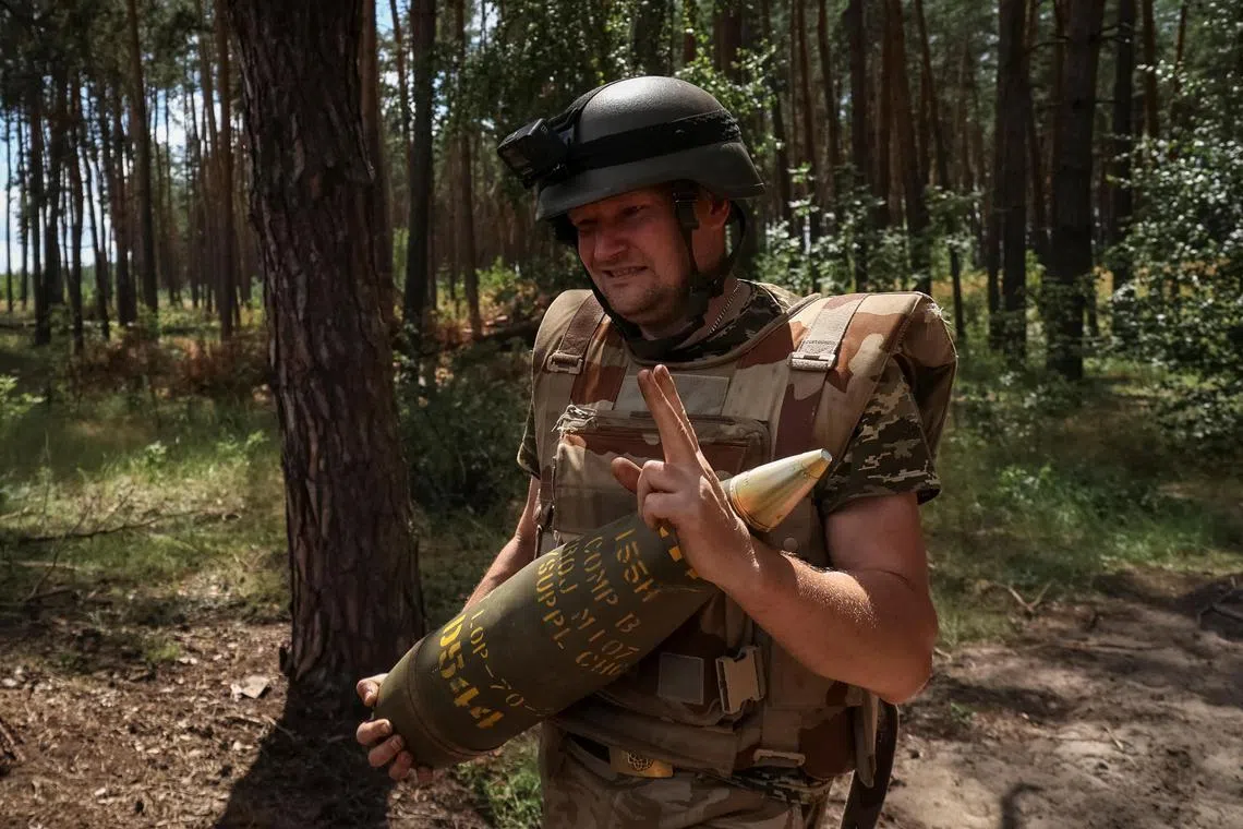 A Ukrainian serviceman carries a shell for an American M109 howitzer, near the city of Kupyansk, in Ukraine's Kharkiv region.