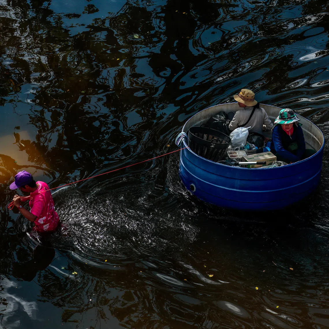 A man pulls a plastic basin carrying people as he navigates the flooded compound of the Sports Authority of Thailand, following heavy rain in Bangkok, Thailand, September 29, 2026. REUTERS/Patipat Janthong TPX IMAGES OF THE DAY