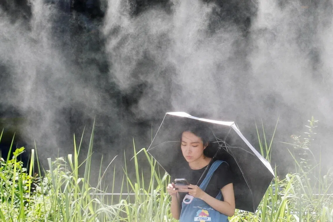 A woman takes a break under a cooling mist during a heatwave in Tokyo on July 15.