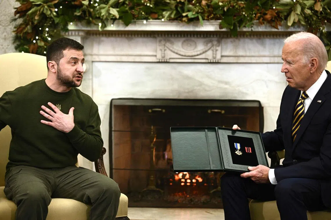 Ukraine's President Volodymyr Zelensky (left) presents the Ukrainian cross for military merit from a Himars captain to US President Joe Biden in the Oval Office of the White House.