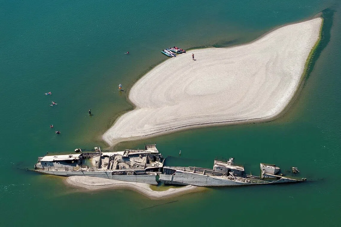 A drone view shows people swimming near a sunken German warship from World War II, exposed due to low Danube River levels caused by drought and extreme heat, in Prahovo, Serbia, July 30, 2026. REUTERS/Djordje Kojadinovic TPX IMAGES OF THE DAY