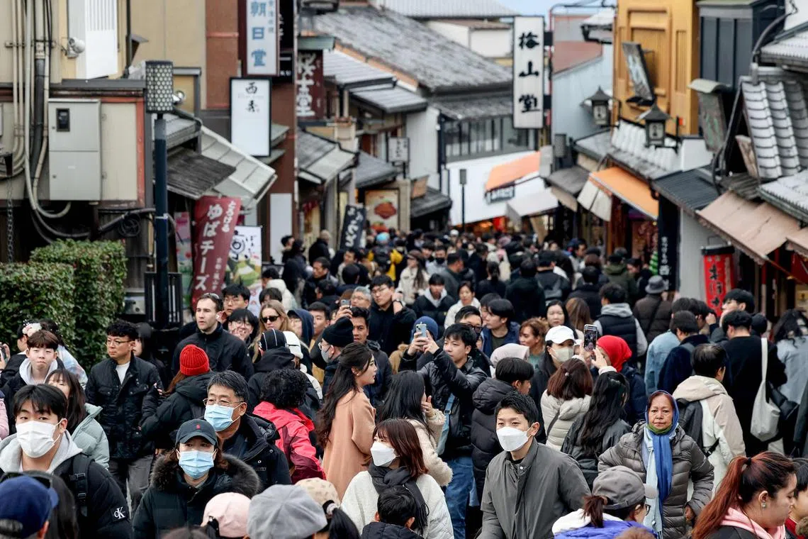 Tourists walk past shops and restaurants up the hill leading to Kiyomizu-dera Temple in the city of Kyoto on Jan 13, 2025. 