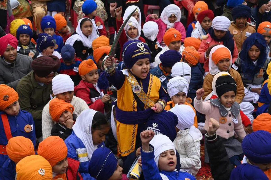 Sikh children wait for the judgement in a turban tying competition in Amritsar on December 25, 2022. PHOTO : AFP