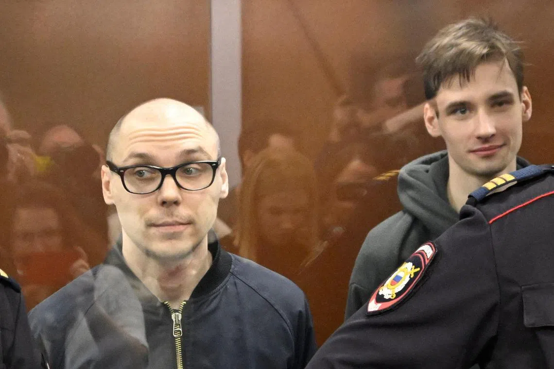 Russian poet Artyom Kamardin (left) and Yegor Shtovba stand inside a glass cage during the announcement of the verdict against them, at a court in Moscow.
