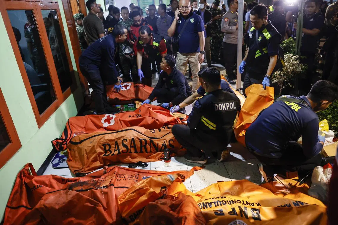 Police officers inspect body bags containing victims, after a blaze at a fuel storage depot in Jakarta, Indonesia.