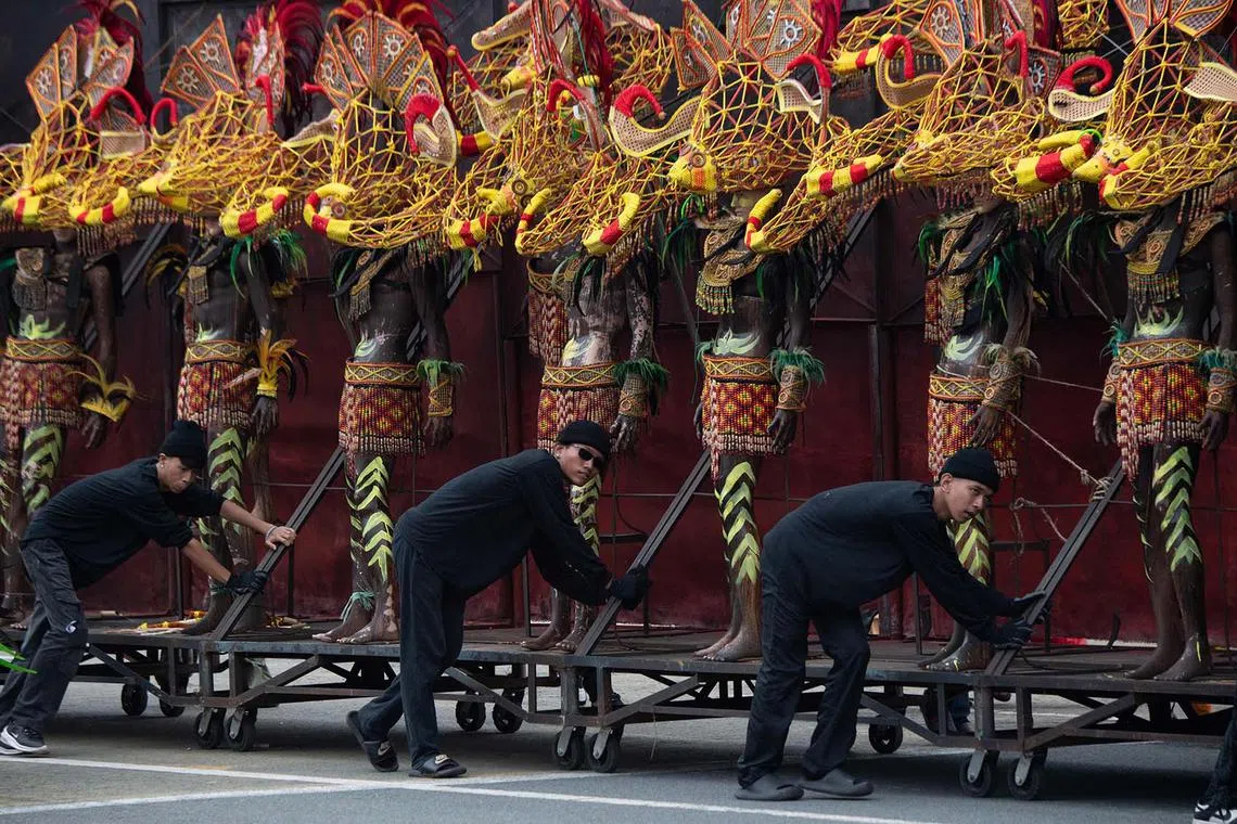 Workers pushing a trolley with mannequins dressed in indigenous costumes during the 127th Independence Day celebration at the Quirino Grandstand in Manila on June 12, 2025. 