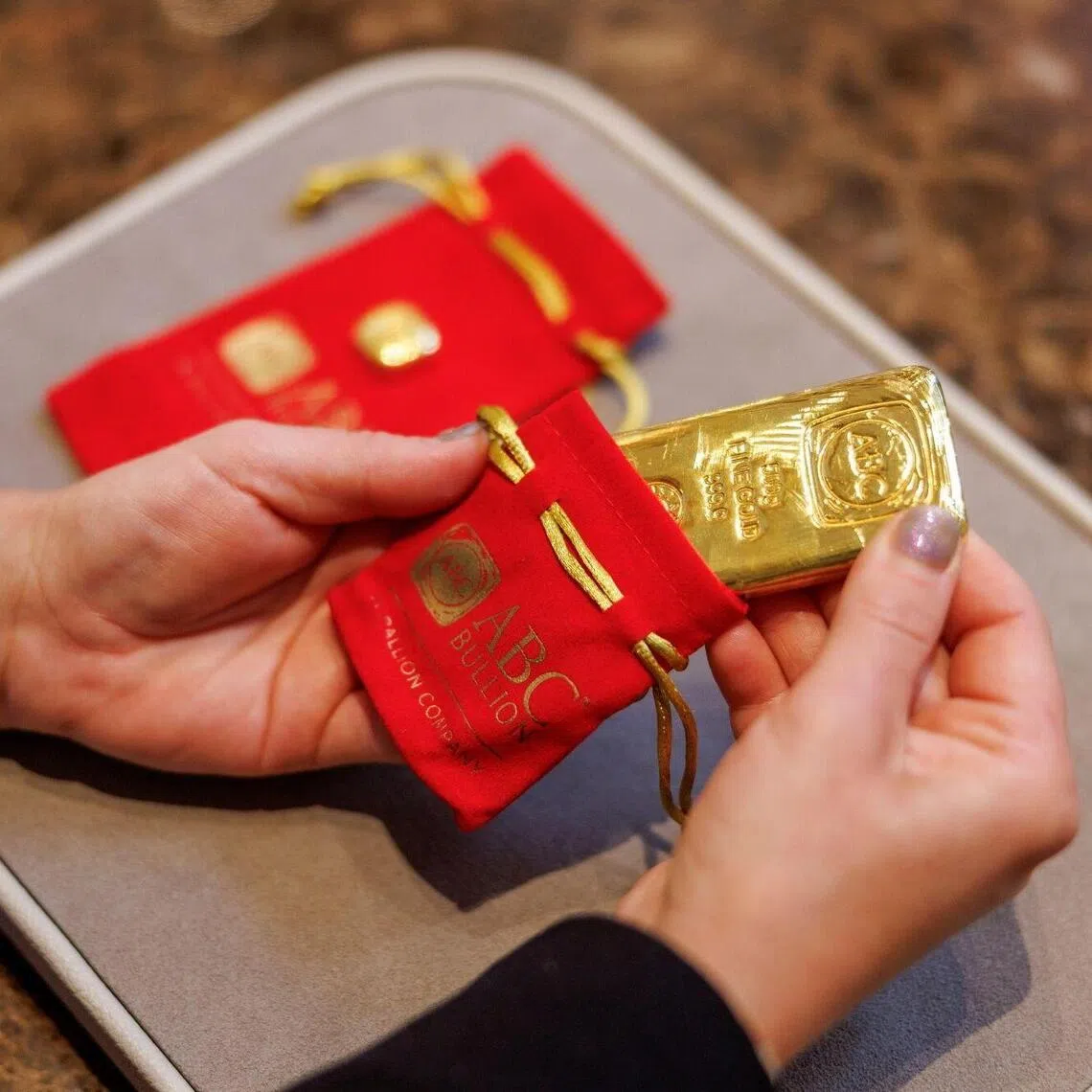 A shop assistant places a 500 gram gold bar in a protective pouch at an ABC Bullion store in Sydney, Australia, on Tuesday, Oct. 21, 2025. Gold held near a record high, finding support despite optimism global trade tensions are easing and hopes the US government will reopen soon. Photographer: Brendon Thorne/Bloomberg