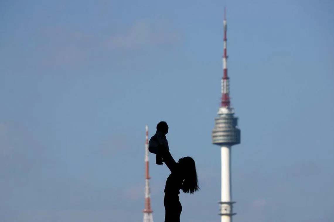 FILE PHOTO: A woman holding up her baby is silhouetted against the backdrop of N Seoul Tower, commonly known as Namsan Tower, in Seoul, South Korea, October 2, 2018.   REUTERS/Kim Hong-Ji/File Photo