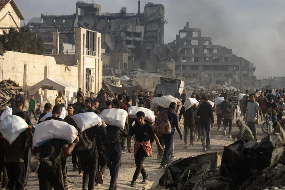Displaced Palestinians carry relief packages along Rashid Street, west of Jabalia, on June 22.