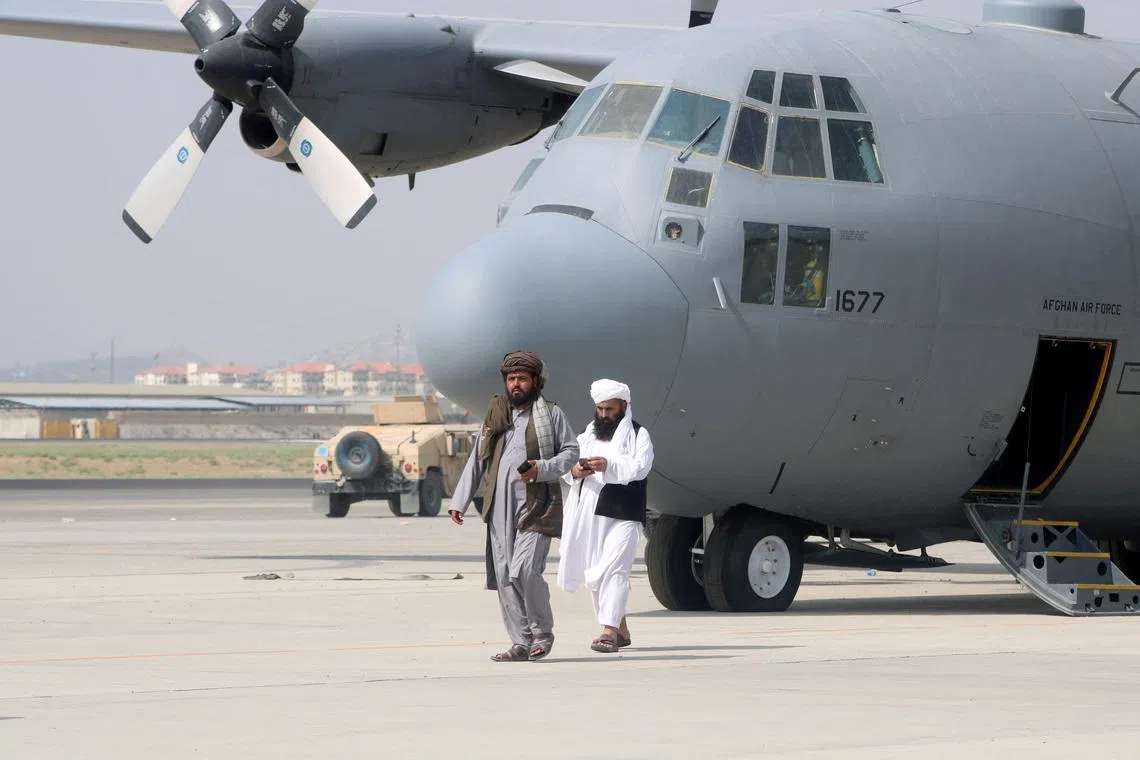 FILE PHOTO: Taliban walk in front of a military airplane a day after the U.S. troops withdrawal from Hamid Karzai International Airport in Kabul, Afghanistan August 31, 2021. REUTERS/Stringer/File Photo