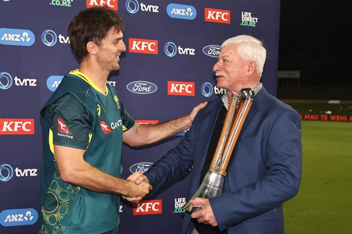 Australia's Mitchell Marsh is presented the Chappell-Hadlee Trophy by former New Zealand cricketer Richard Hadlee following the third Twenty20 cricket match between the two sides at Bay Oval in Mount Maunganui on Oct 4, 2025.