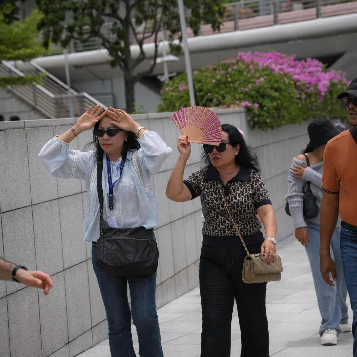 People shield themselves from the sun during a hot day at the Merlion Park on March 26.