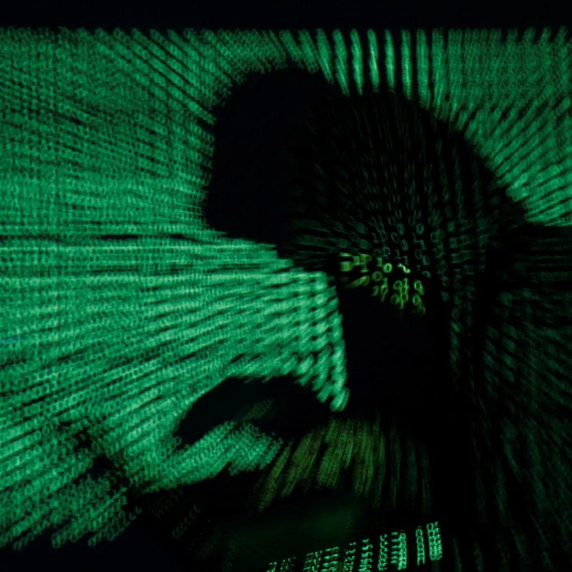 A hooded man holds a laptop computer as cyber code is projected on him in this illustration picture taken on May 13, 2017. REUTERS/Kacper Pempel/Illustration