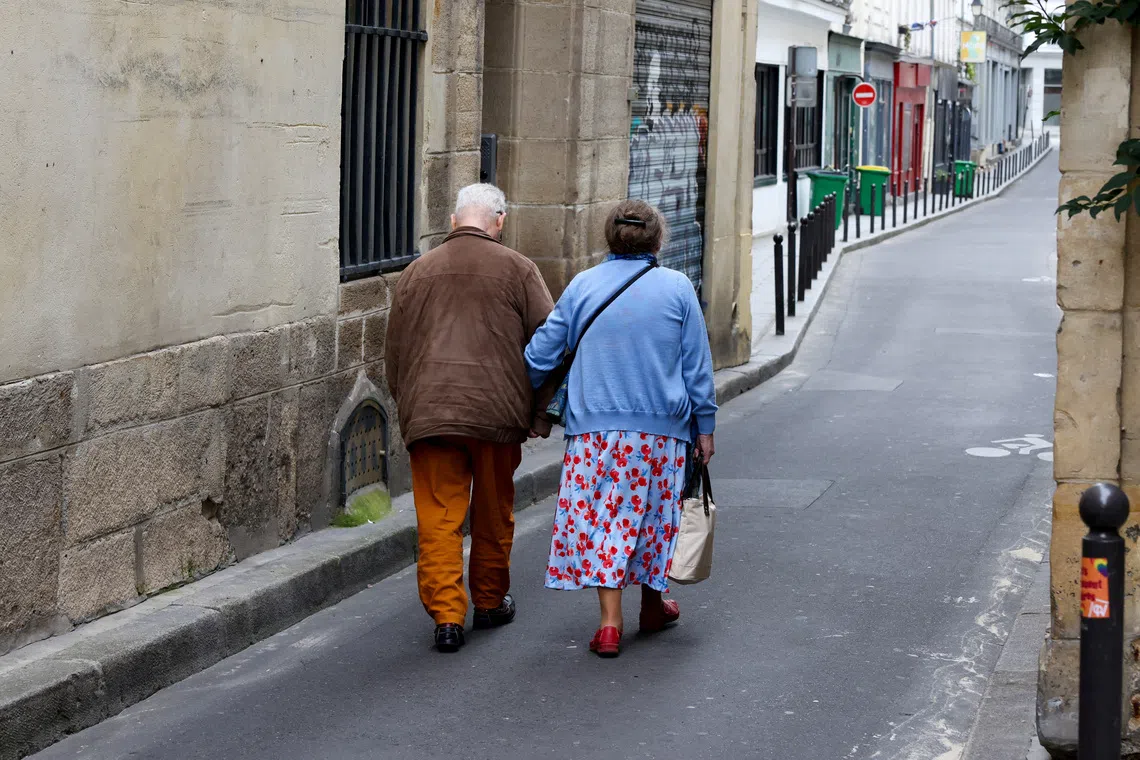 Two elderly people walk arm-in-arm down a side street in Paris, France, July 14, 2024. REUTERS/Kevin Coombs