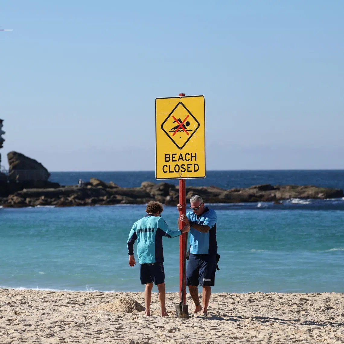 Lifeguards erecting a sign that says “Beach Closed” following a shark attack at Coogee Beach in Sydney, Australia, on June 13, 2026.