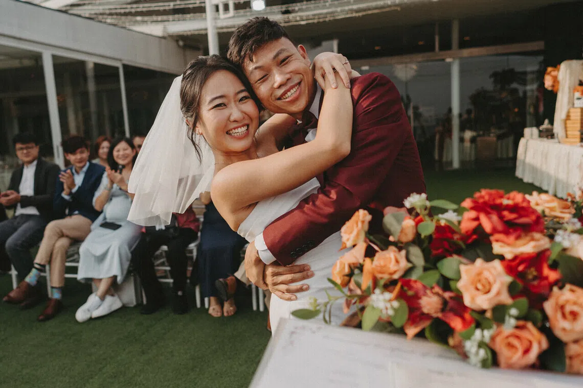 Ms Dione Chen and Mr Glen Ong share a joyful embrace at their garden-themed wedding, surrounded by family and friends.