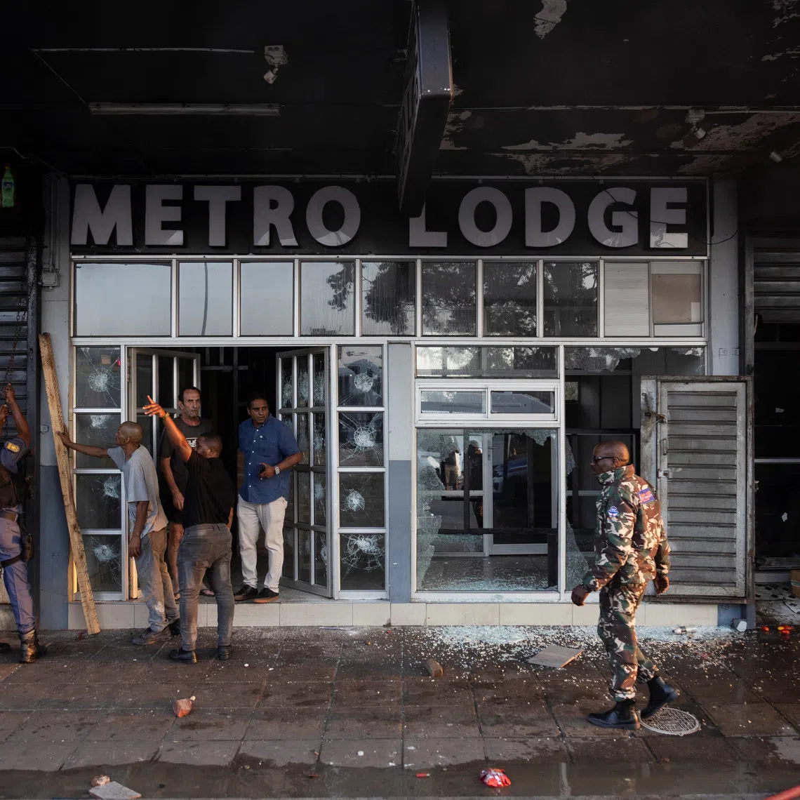 Police and security survey the damage done to a business during anti-immigrant protests in Durban, South Africa, on Oct 8.