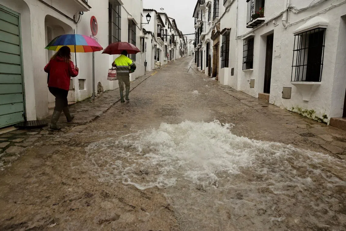 People walk along a flooded street due to heavy rains, as storm Leonardo hits parts of Spain, in Grazalema, Spain, February 5, 2026. REUTERS/Jon Nazca