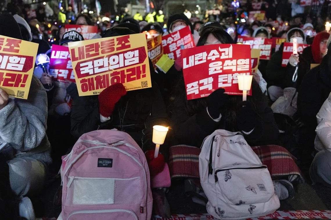 Protesters hold up placards calling for the impeachment of President Yoon Suk Yeol outside the National Assembly.