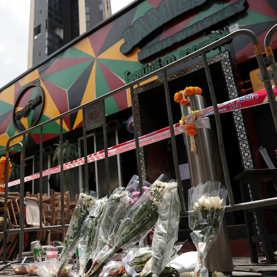 Flowers and offerings are placed outside Rong Beer Na Lat Phrao bar in Bangkok, the site of a deadly fire, to pay tribute to victims who lost their lives.