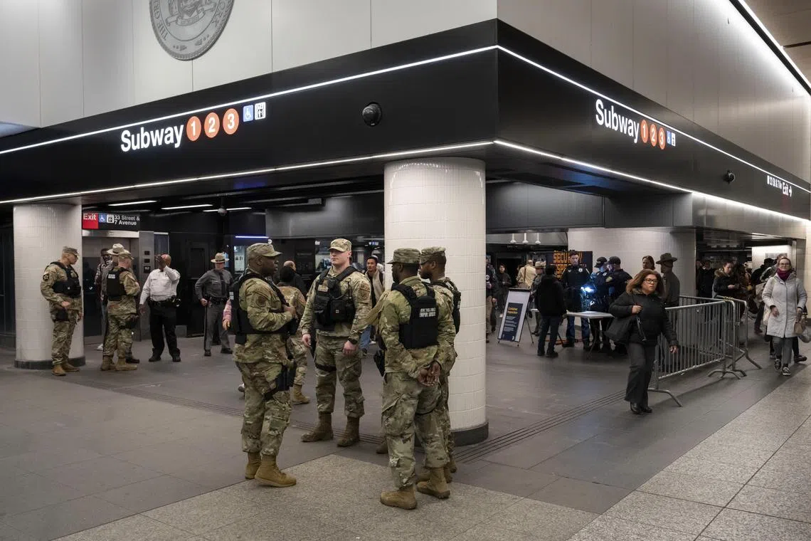 Members of the State Police and National Guard stand by as the Metropolitan Transit Authority police search bags at a security checkpoint at Penn Station in New York, on March 7. Some 1,000 members of the National Guard and the State Police are patrolling New York City’s subway system in an effort to help people feel safer.