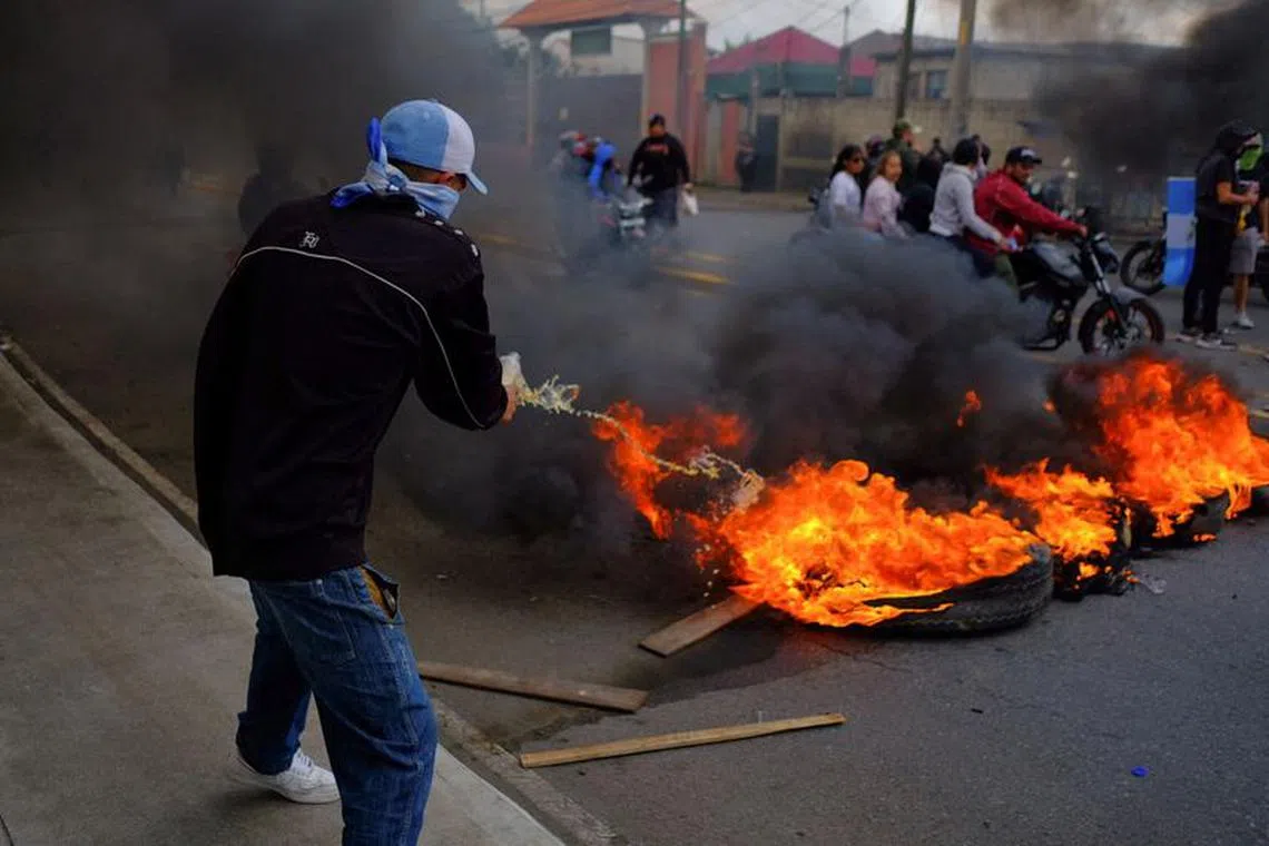 A man pours a liquid on a burning barricade, as part of a national strike to demand the resignation of authorities from the attorney general's office, in Guatemala City, Guatemala October 10, 2023. REUTERS/Josue Decavele/File Photo