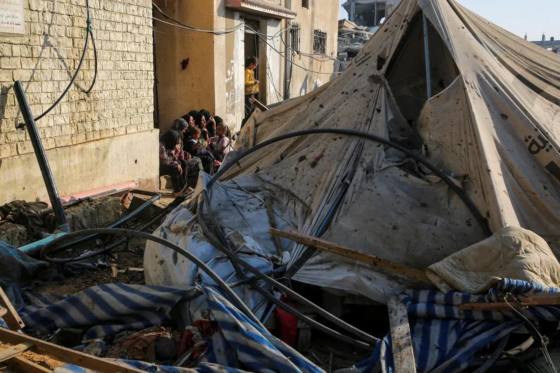 Palestinians sit near a damaged tent at the site of an Israeli strike near a school sheltering displaced people, amid Israel-Hamas conflict, in Khan Younis in the southern Gaza Strip July 10, 2024. REUTERS/Hatem Khaled