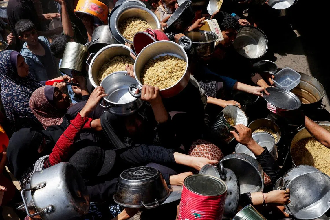 Palestinians gather as they receive food cooked by a charity kitchen, in Khan Younis, southern Gaza Strip, April 29, 2025. REUTERS/Hatem Khaled