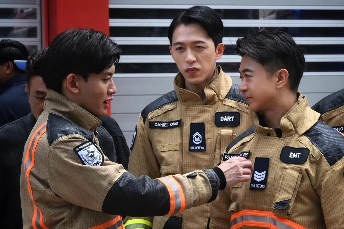 Noah Yap (left) adjusting the uniform for Maxi Lim ( right) as Tosh Zhang looks on during a photo call for Jack Neo’s upcoming film Ah Boys To Firefighters.