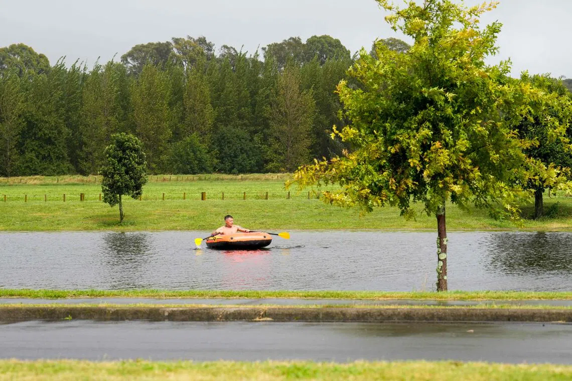 A photo taken on February 14, 2023 shows a man paddling a boat across floodwaters in the North Island city of Napier. - New Zealand declared a national state of emergency on February 14 as Cyclone Gabrielle swept away roads, inundated homes and left more than 100,000 people without power. (Photo by AFP) / New Zealand OUT
