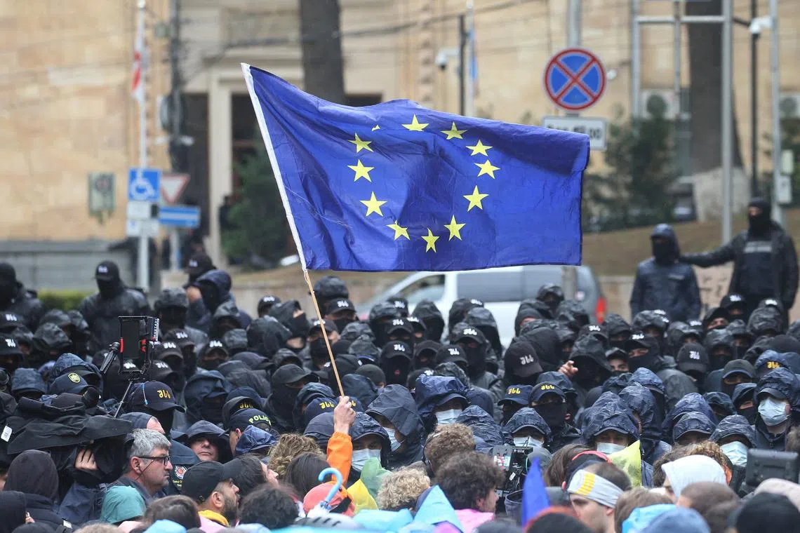 FILE PHOTO: A demonstrator holds a European Union flag in front of law enforcement officers during a rally to protest against a bill on \"foreign agents\" in Tbilisi, Georgia, May 14, 2024. REUTERS/Irakli Gedenidze/File Photo