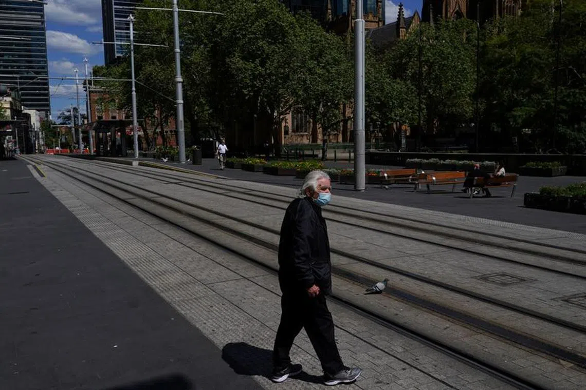 FILE PHOTO: A pedestrian wearing a protective face mask crosses tram lines in the city centre during a lockdown to curb the spread of a coronavirus disease (COVID-19) outbreak in Sydney, Australia, September 24, 2021.  REUTERS/Loren Elliott/file photo