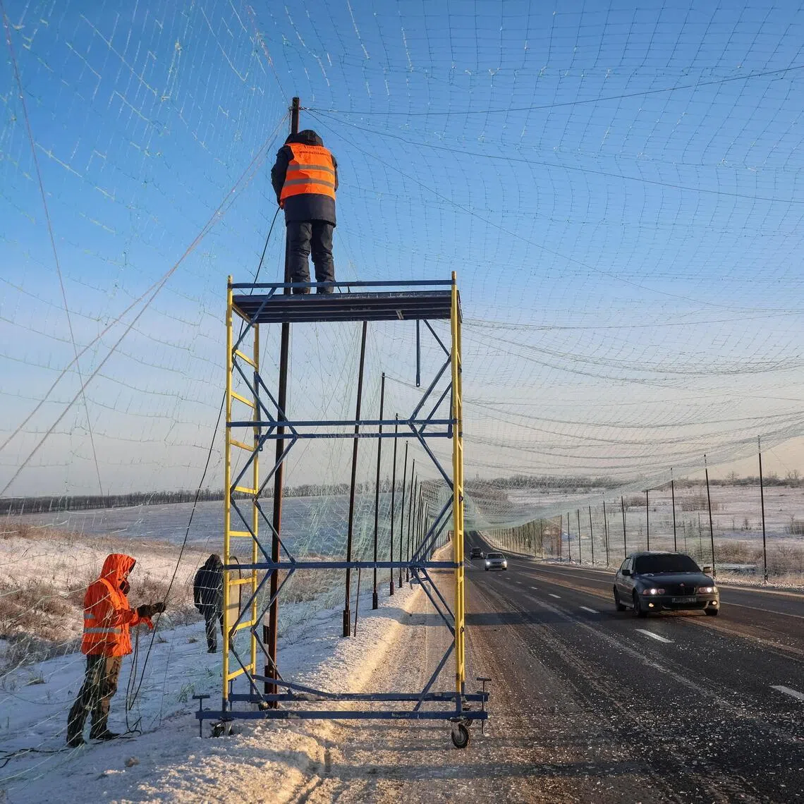 Workers installing anti-drone nets over a road near the city of Kharkiv on Feb 2, amid Russia's invasion of Ukraine.
