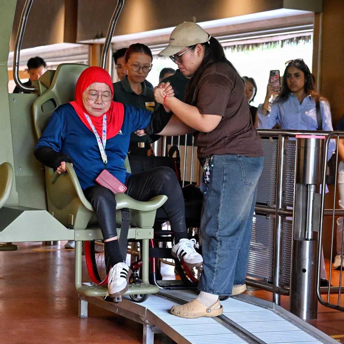 Aisah Binti Ibrahim (centre), 79, member of Disabled People’s Association, boarding the Canopy Glider with the help of her caregiver Sri Lestari (right), 30, at Rainforest Wild Adventure East on Sept 15.