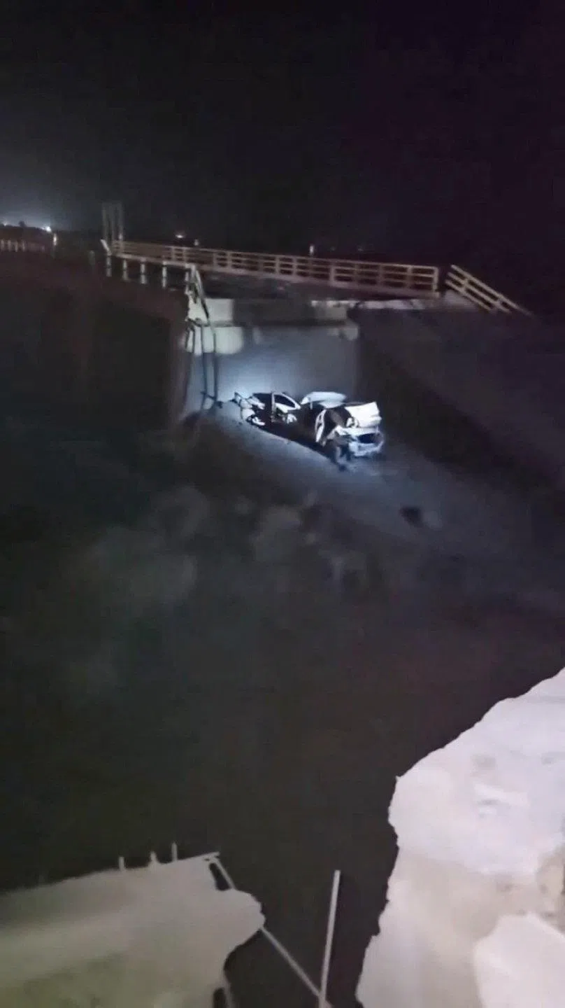 A light shines on a damaged vehicle and a collapsed portion of a bridge in the aftermath of a strike in Bandar Khamir, in Iran’s Hormozgan province, on July 16.