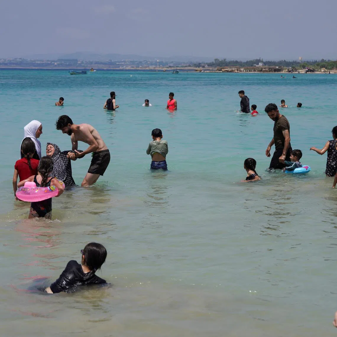 People swim at a public beach in Latakia, Syria June 12, 2025. REUTERS/Karam Al-Masri