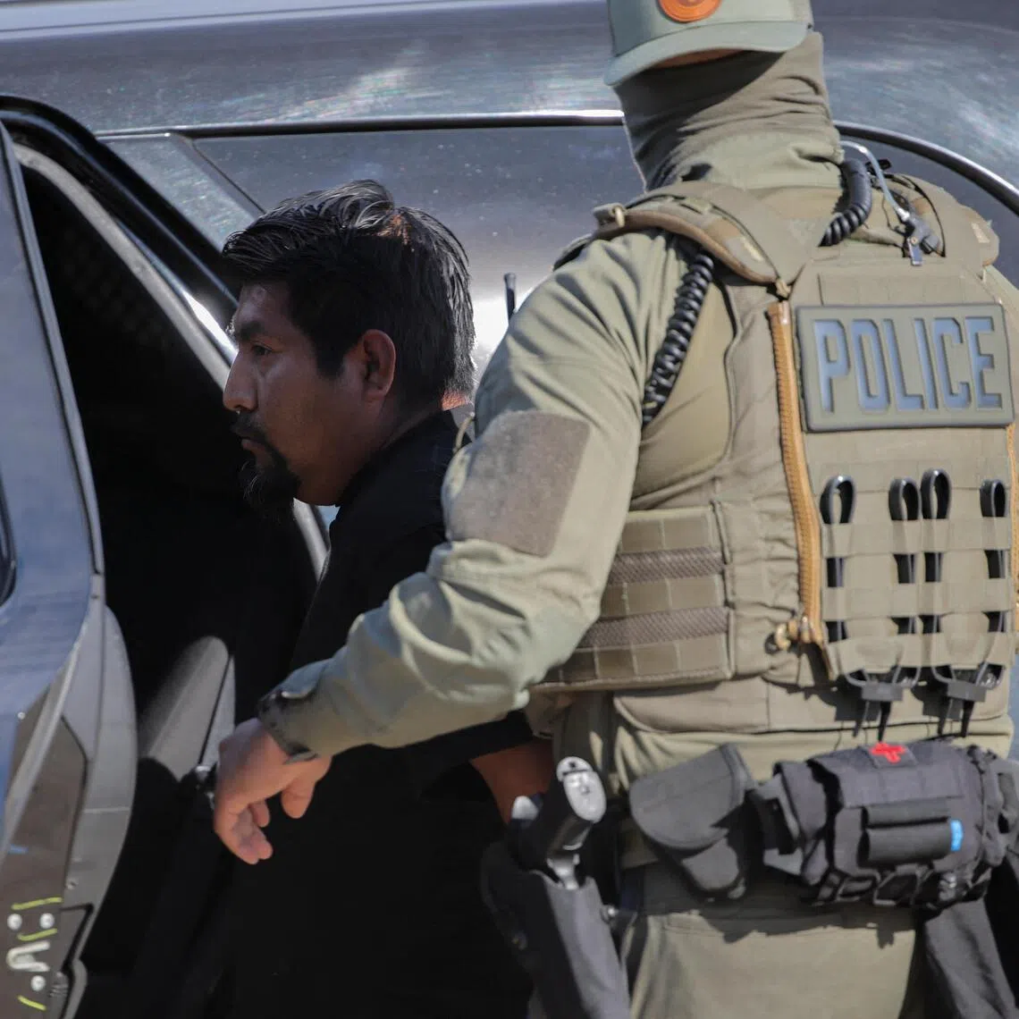 A US Immigration and Customs Enforcement (ICE) agent detaining a man during an immigration raid in Thermal, California, on Dec 19.