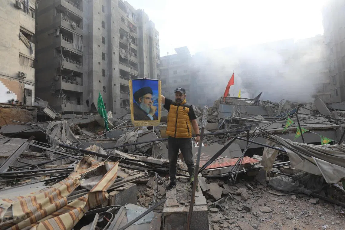 A man carries a portrait of Hezbollah's slain leader Hassan Nasrallah as he stands amid the rubble of a building, flattened in an overnight Israeli airstrike on Beirut’s southern suburbs on Nov 1.