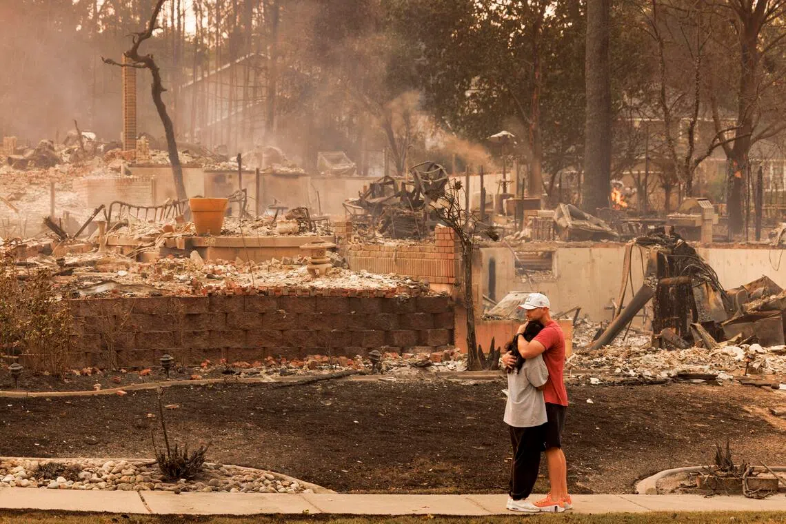 Christine and Bryan Farris hug after all of their belongings burned from the Old Trail wildfire in Spokane, Wash., on Sunday, Aug. 2, 2026. Hundreds of structures were destroyed and thousands of people in Spokane County, Wash., remained under evacuation orders on Sunday as firefighters continued their efforts to knock back and control several blazes in the area. (John Stember/The New York Times)