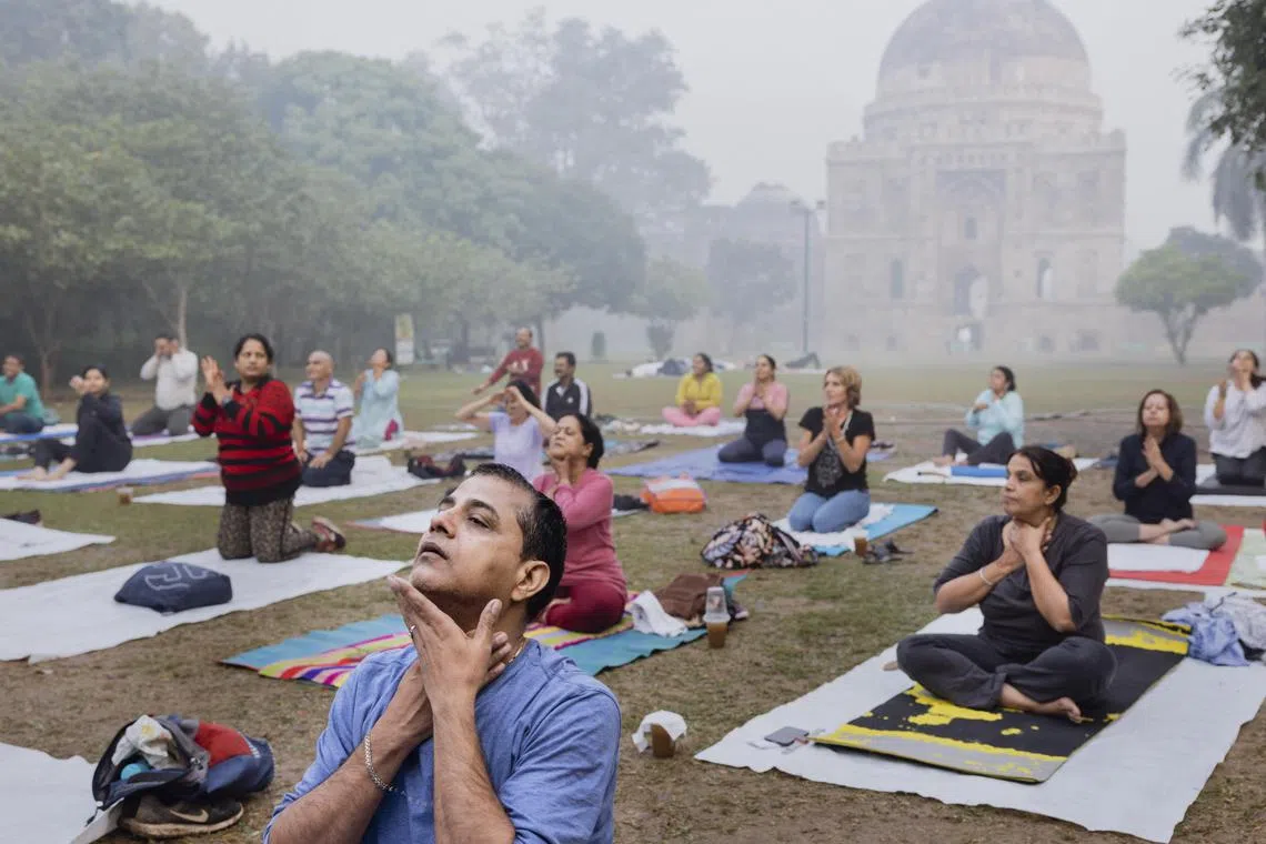 People practicing yoga in Lodhi Garden with smog lingering over India’s capital city, New Delhi.