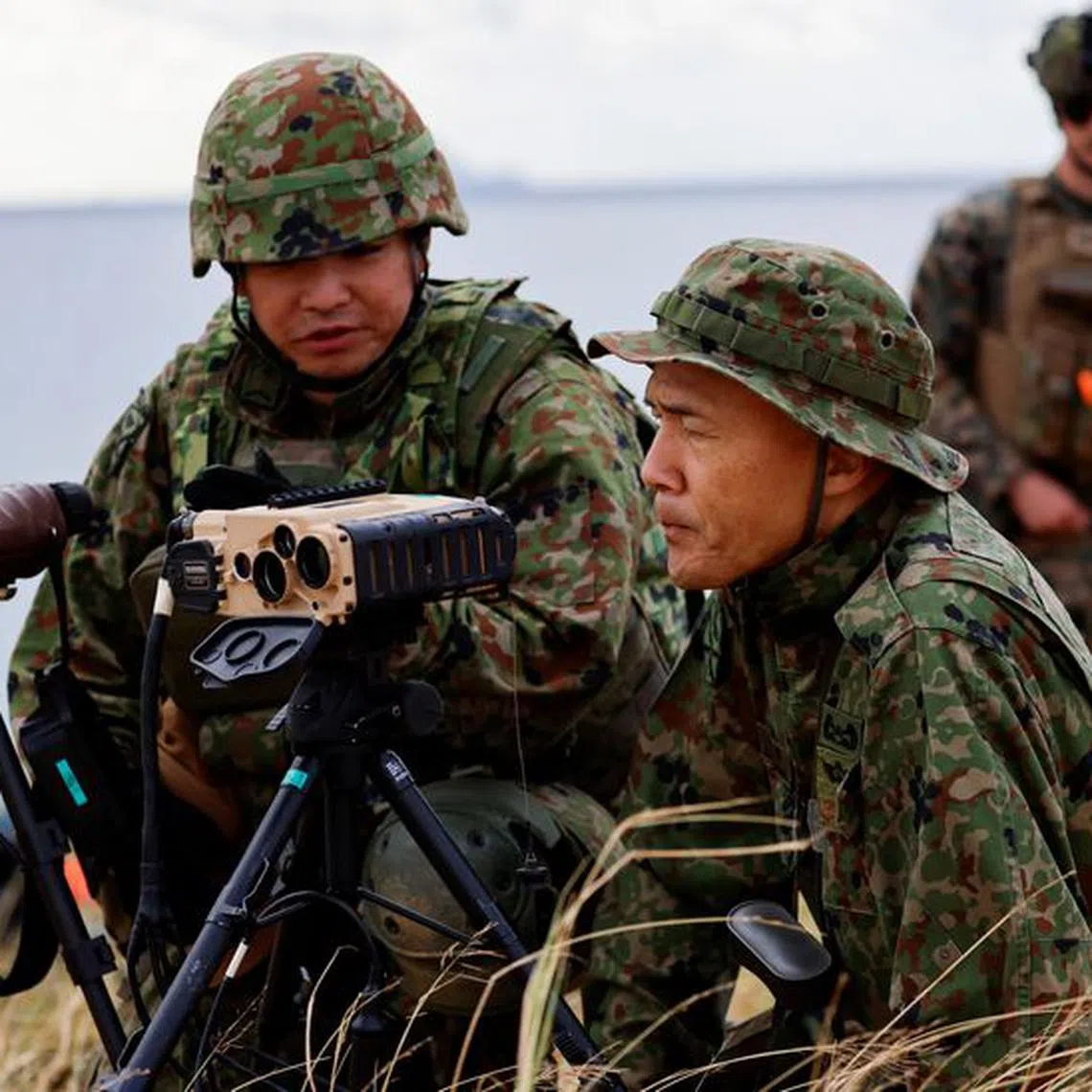 Soldiers of Japanese Ground Self-Defense Force's (JGSDF) Amphibious Rapid Deployment Brigade (ARDB), Japan's first marine unit since World War Two, take part in a military drill as a U.S. Marine personnel looks on, at an uninhabited Irisuna island close to Okinawa, Japan, November 15, 2023. REUTERS/Issei Kato