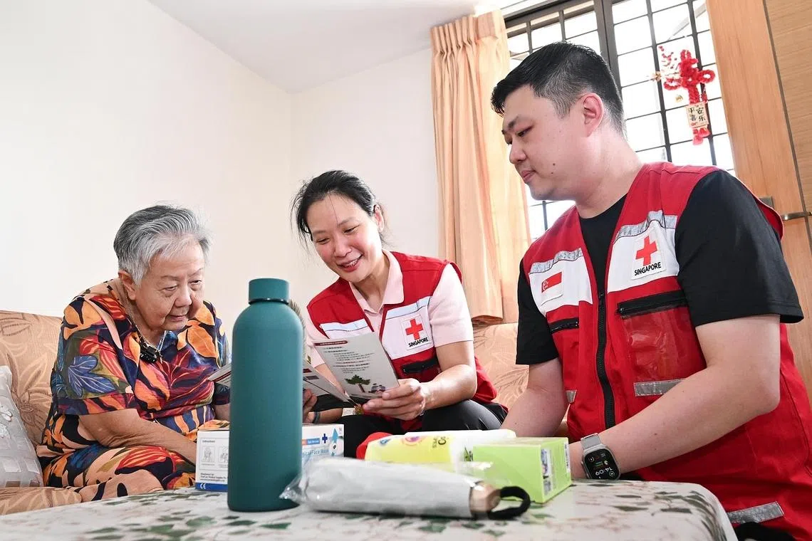 (From left) Madam Magdalene Tan with Singapore Red Cross representatives Charis Chan and Alan Phuang at her flat on April 6.